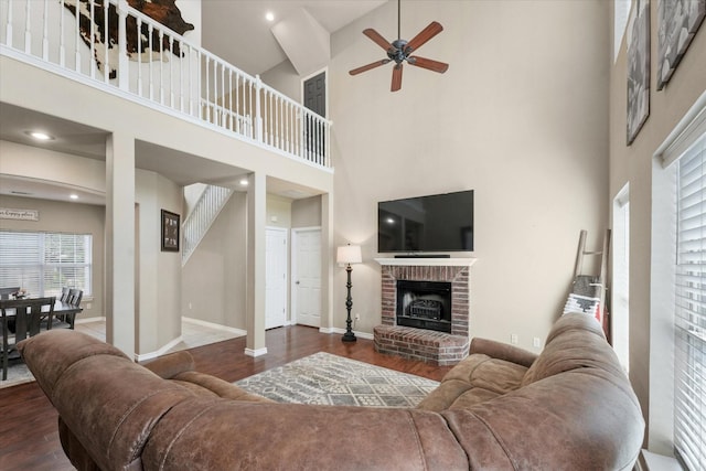 210 Sendero Dr, Waxahachie, TX 75165 - living room with wood finished floors, ceiling fan, a towering ceiling, a fireplace, and baseboards