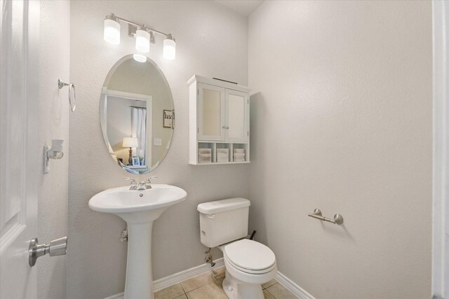 210 Sendero Dr, Waxahachie, TX 75165 - half bathroom featuring tile patterned floors, toilet, baseboards, and a sink