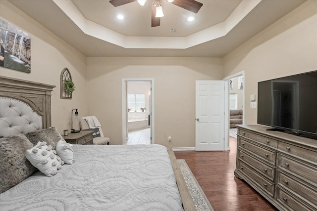 210 Sendero Dr, Waxahachie, TX 75165 - bedroom featuring dark wood-style floors, a tray ceiling, baseboards, connected bathroom, and a ceiling fan