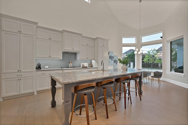1306 Blue Lake Blvd, Arlington, TX 76005 - kitchen with high vaulted ceiling, light wood finished floors, a sink, tasteful backsplash, and a kitchen bar