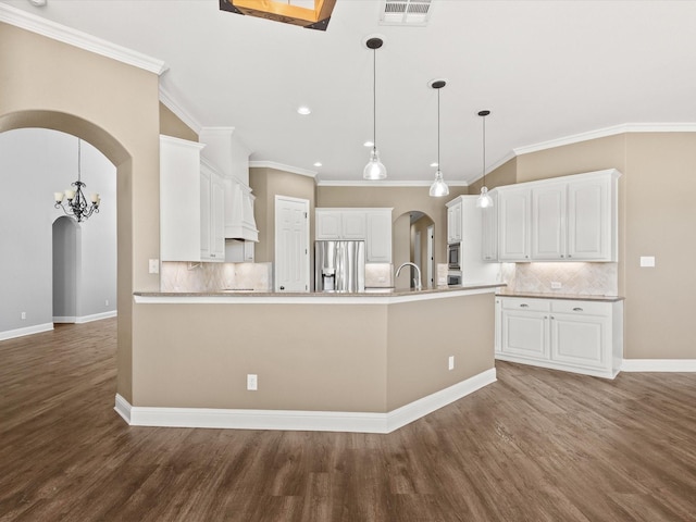 1105 Crown Valley Dr, Weatherford, TX 76087 - kitchen with appliances with stainless steel finishes, wood finished floors, arched walkways, tasteful backsplash, and a peninsula
