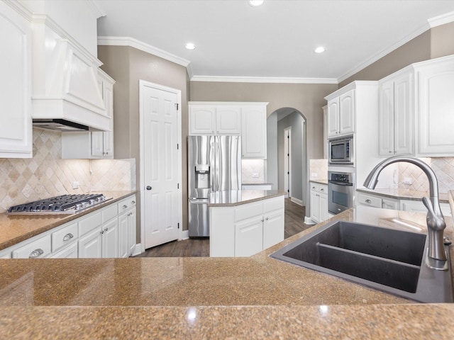 1105 Crown Valley Dr, Weatherford, TX 76087 - kitchen with appliances with stainless steel finishes, a sink, arched walkways, white cabinets, and ornamental molding