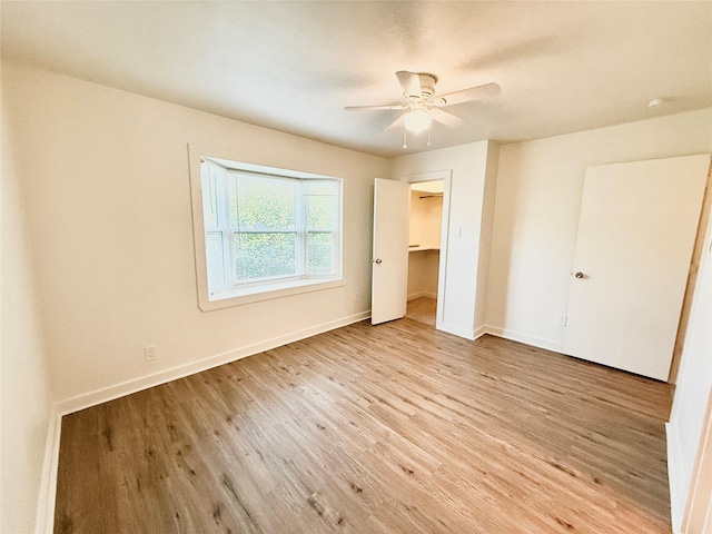 2807 Throckmorton St Unit 101, Dallas, TX 75219 - unfurnished bedroom with wood finished floors, baseboards, ceiling fan, and a walk in closet
