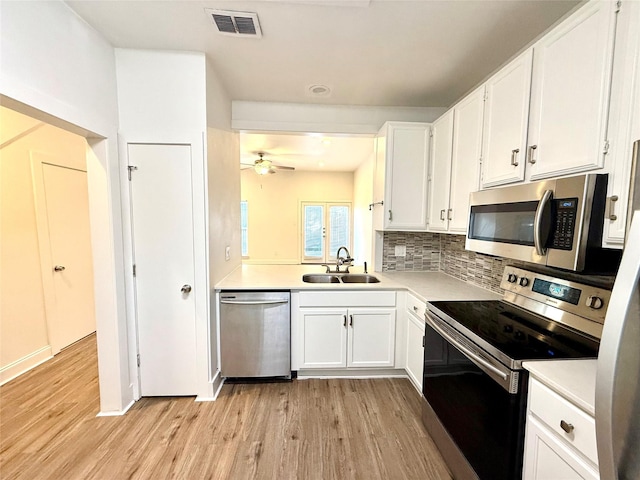 2807 Throckmorton St Unit 101, Dallas, TX 75219 - kitchen featuring stainless steel appliances, a sink, light wood-style flooring, white cabinets, and light countertops