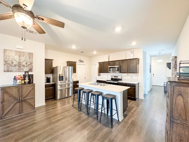 3225 Conley Ct, Mesquite, TX 75126 - kitchen with appliances with stainless steel finishes, ceiling fan, dark brown cabinets, wood finished floors, and a breakfast bar area