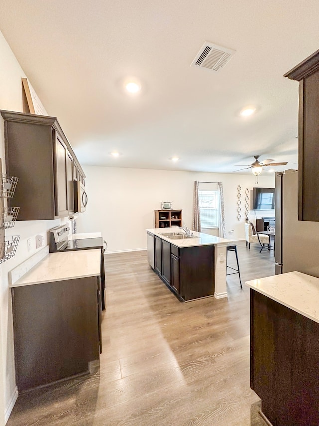 3225 Conley Ct, Mesquite, TX 75126 - kitchen featuring appliances with stainless steel finishes, dark brown cabinetry, a sink, light wood finished floors, and light countertops