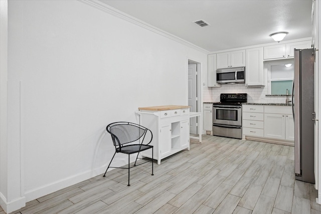 5409 Queens Ct, Lake Dallas, TX 75065 - kitchen with appliances with stainless steel finishes, open shelves, white cabinetry, light wood-type flooring, and ornamental molding