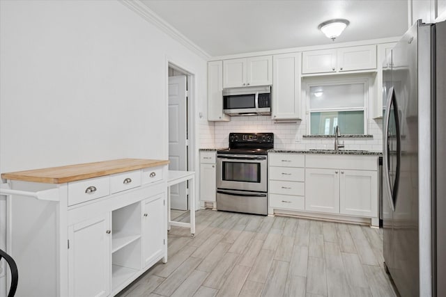 5409 Queens Ct, Lake Dallas, TX 75065 - kitchen with appliances with stainless steel finishes, a sink, white cabinets, backsplash, and crown molding