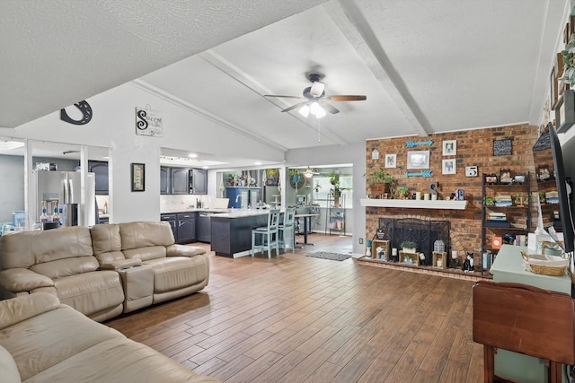 7028 Whitewood Dr, Fort Worth, TX 76137 - living area featuring a ceiling fan, wood finished floors, a fireplace, and a textured ceiling