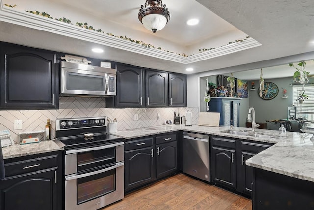 7028 Whitewood Dr, Fort Worth, TX 76137 - kitchen with stainless steel appliances, a sink, light stone counters, light wood-style floors, and recessed lighting