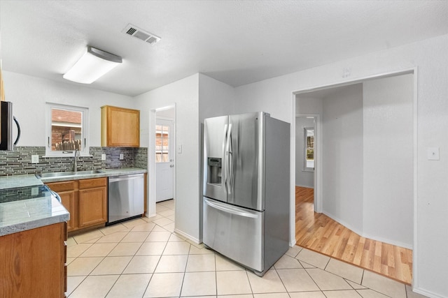 415 Blueberry Hill Ln, Mansfield, TX 76063 - kitchen with appliances with stainless steel finishes, a sink, light tile patterned floors, decorative backsplash, and baseboards