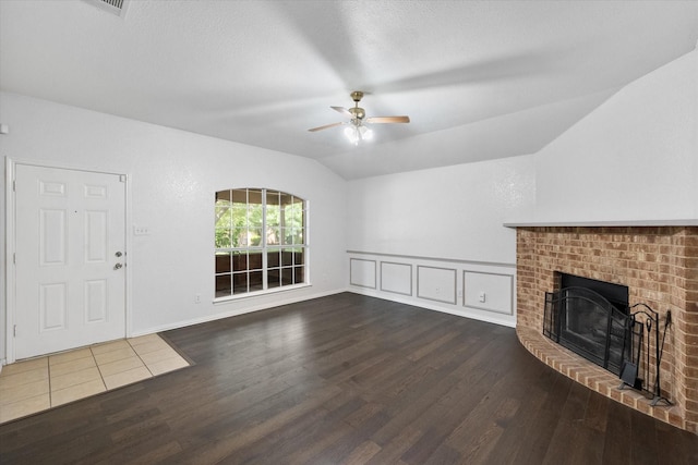 415 Blueberry Hill Ln, Mansfield, TX 76063 - unfurnished living room with wood finished floors, vaulted ceiling, ceiling fan, a fireplace, and a wainscoted wall