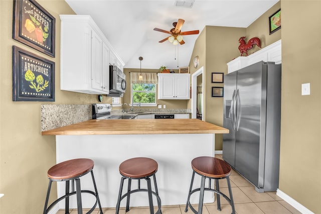 121 Sanchez Creek Ct, Weatherford, TX 76088 - kitchen featuring stainless steel appliances, a peninsula, white cabinetry, butcher block countertops, and vaulted ceiling