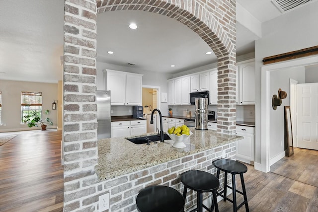 3964 Hunter Peak Rd, Fort Worth, TX 76262 - kitchen with appliances with stainless steel finishes, decorative columns, a sink, wood finished floors, and arched walkways
