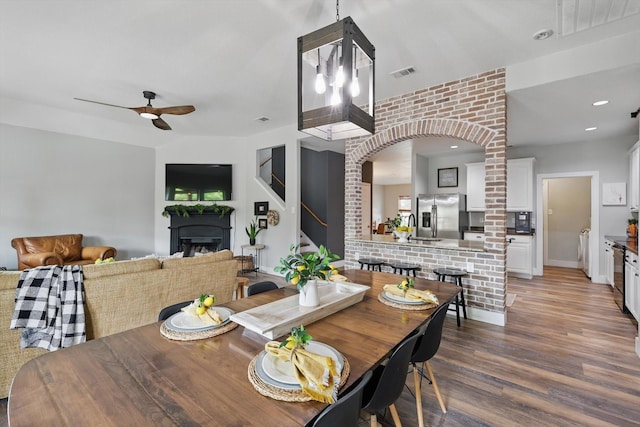 3964 Hunter Peak Rd, Fort Worth, TX 76262 - dining space featuring a fireplace, wood finished floors, a ceiling fan, and arched walkways