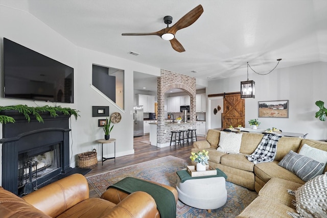 3964 Hunter Peak Rd, Fort Worth, TX 76262 - living room with a barn door, ceiling fan, wood finished floors, a fireplace, and baseboards
