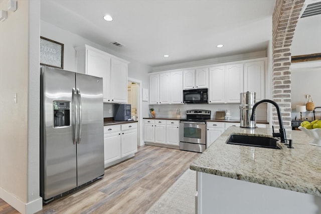 3964 Hunter Peak Rd, Fort Worth, TX 76262 - kitchen with appliances with stainless steel finishes, a sink, light wood finished floors, white cabinets, and dark stone countertops