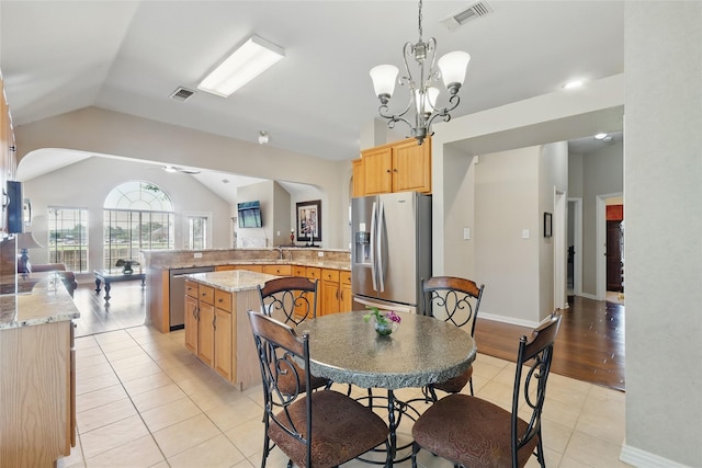 110 Lakeshore Dr, Trophy Club, TX 76262 - kitchen featuring appliances with stainless steel finishes, light tile patterned flooring, vaulted ceiling, a peninsula, and a chandelier