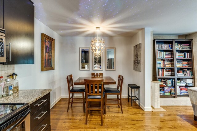 5816 Birchbrook Dr Unit 118, Dallas, TX 75206 - dining area featuring light wood-type flooring, a chandelier, and baseboards