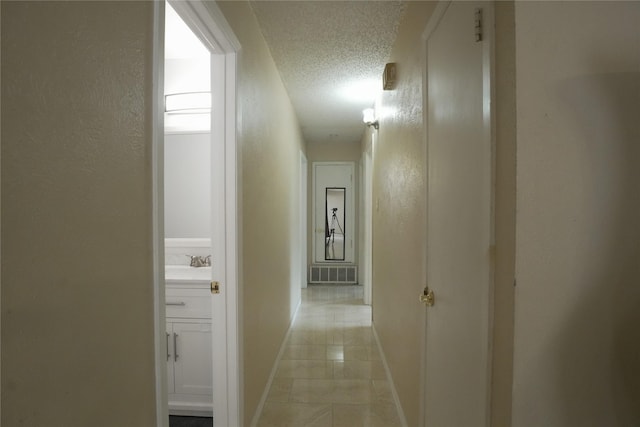 706 Midway Dr W, Euless, TX 76039 - hallway featuring a textured ceiling, a textured wall, baseboards, a sink, and light tile patterned floors