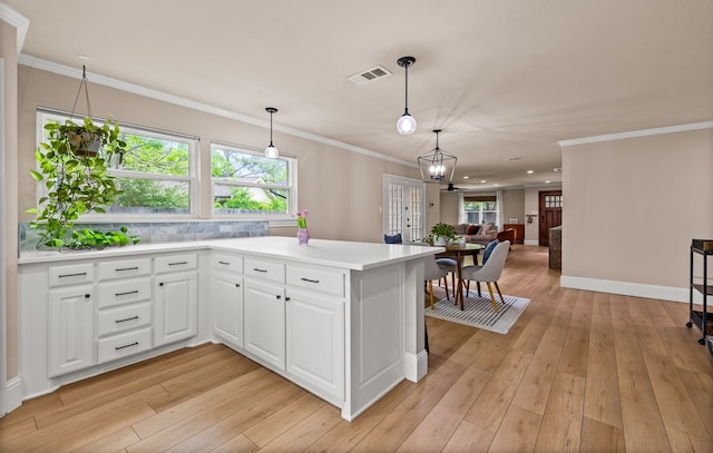 3455 Timberview Rd, Dallas, TX 75229 - kitchen featuring light wood-style flooring, light countertops, white cabinetry, hanging light fixtures, and crown molding