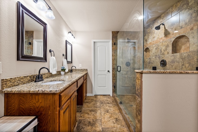 3455 Timberview Rd, Dallas, TX 75229 - bathroom featuring tiled shower, double vanity, stone finish flooring, baseboards, and a textured ceiling