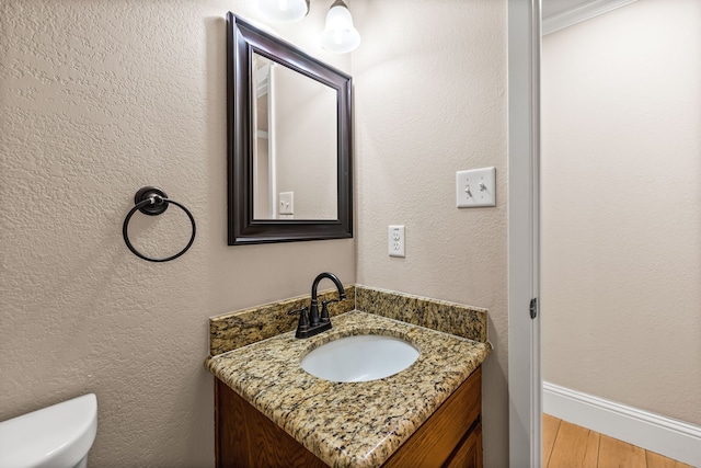 3455 Timberview Rd, Dallas, TX 75229 - half bathroom with vanity, toilet, wood finished floors, and baseboards