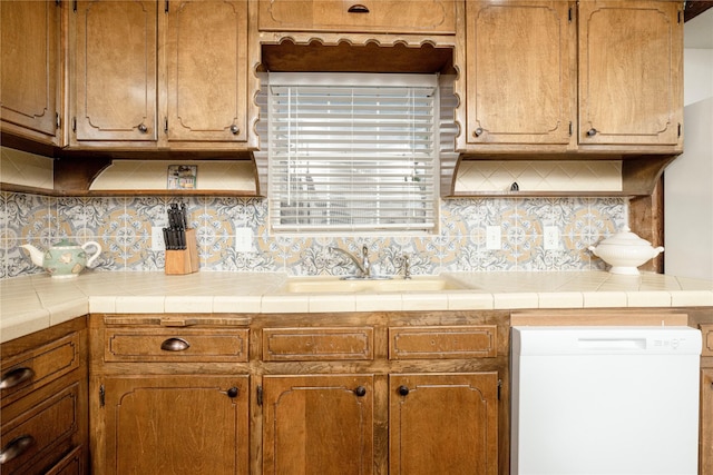 3410 Ellis Ave, Fort Worth, TX 76106 - kitchen featuring dishwasher, tasteful backsplash, light countertops, a sink, and brown cabinetry