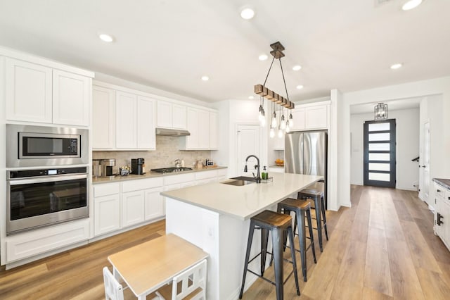 1213 Palmetto Dr, Forney, TX 75126 - kitchen featuring appliances with stainless steel finishes, a sink, under cabinet range hood, decorative backsplash, and white cabinetry