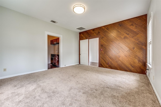 1833 Mcmillan Ave, Dallas, TX 75206 - unfurnished bedroom featuring carpet flooring, baseboards, and wood walls