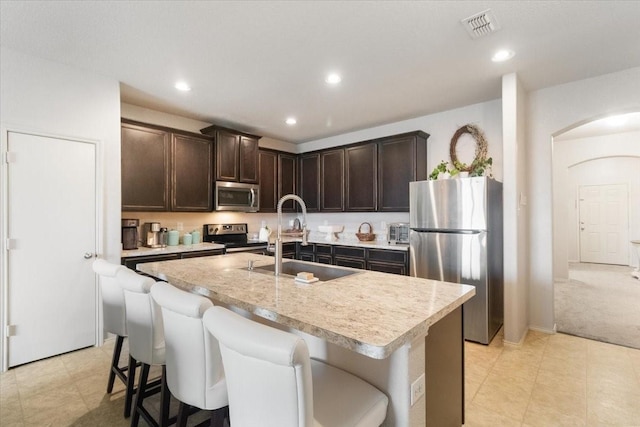2113 Brenham Dr, Forney, TX 75126 - kitchen featuring appliances with stainless steel finishes, a sink, arched walkways, dark brown cabinets, and light countertops