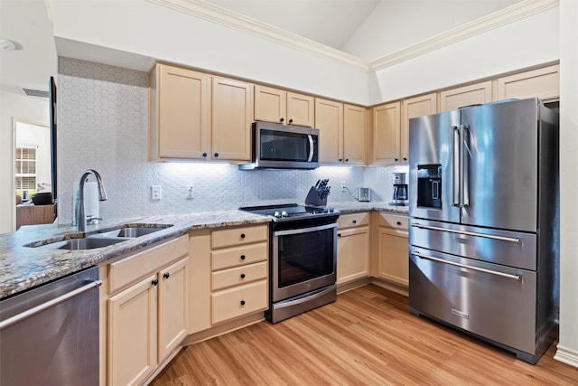 908 Bridges Dr, Arlington, TX 76012 - kitchen featuring stainless steel appliances, a sink, vaulted ceiling, light brown cabinets, and light wood-style flooring