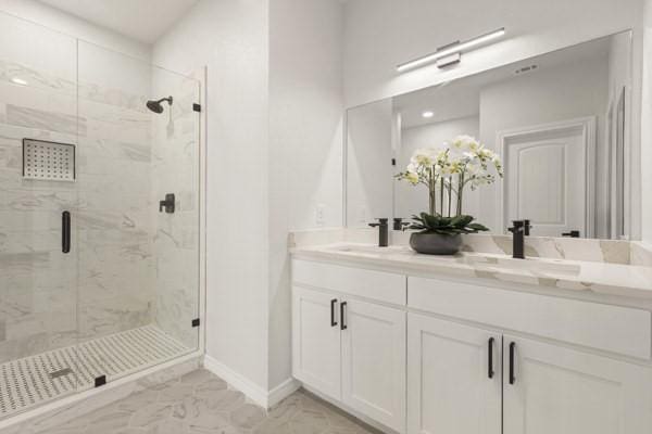 304 Pearl Harbor St, Tool, TX 75143 - bathroom with marble look tile flooring, a marble finish shower, double vanity, and baseboards