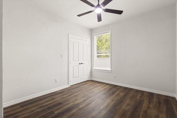 304 Pearl Harbor St, Tool, TX 75143 - unfurnished bedroom featuring baseboards, dark wood-style flooring, a closet, and ceiling fan