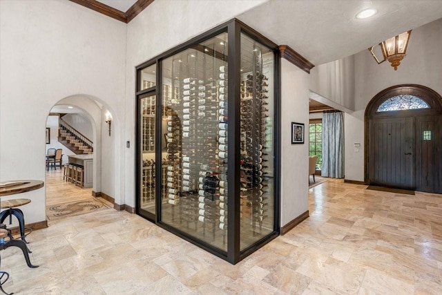 5909 Kittansett Ct, Fort Worth, TX 76132 - wine area featuring arched walkways, stone tile flooring, a high ceiling, baseboards, and crown molding