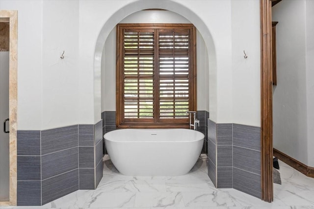 5909 Kittansett Ct, Fort Worth, TX 76132 - full bathroom featuring marble finish flooring, a wainscoted wall, a freestanding bath, and tile walls