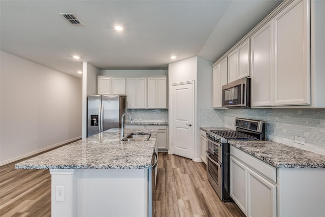 788 Cascade Ln, Princeton, TX 75407 - kitchen featuring stainless steel appliances, a sink, light wood-style floors, decorative backsplash, and light stone countertops