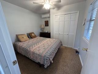 2319 N Wind Dr, Tool, TX 75143 - bedroom with a closet, a wall unit AC, ceiling fan, carpet flooring, and baseboards