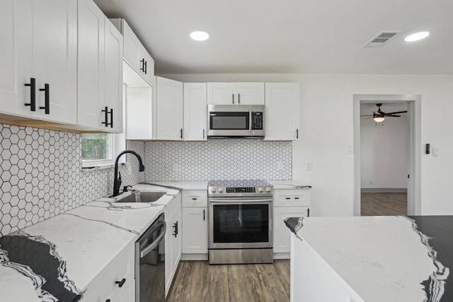 112 Gordon Dr, Azle, TX 76020 - kitchen featuring appliances with stainless steel finishes, a sink, wood finished floors, a ceiling fan, and white cabinetry