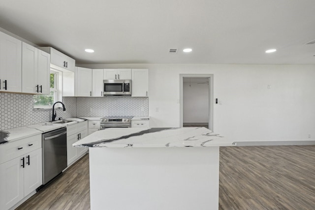 112 Gordon Dr, Azle, TX 76020 - kitchen with appliances with stainless steel finishes, a sink, wood finished floors, light stone countertops, and a kitchen island