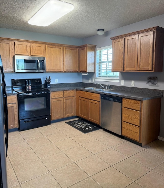 240 County Road 12550, Paris, TX 75462 - kitchen with stainless steel appliances, a sink, a textured ceiling, dark countertops, and brown cabinetry