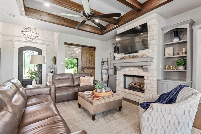 139 County Road 2525, Decatur, TX 76234 - living room featuring a barn door, beamed ceiling, wood finished floors, a ceiling fan, and a fireplace