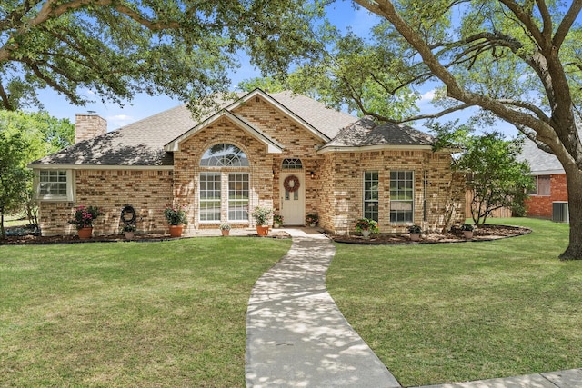 509 Windsor Way, Rockwall, TX 75087 - view of front of property with central AC, brick siding, roof with shingles, a front yard, and a chimney