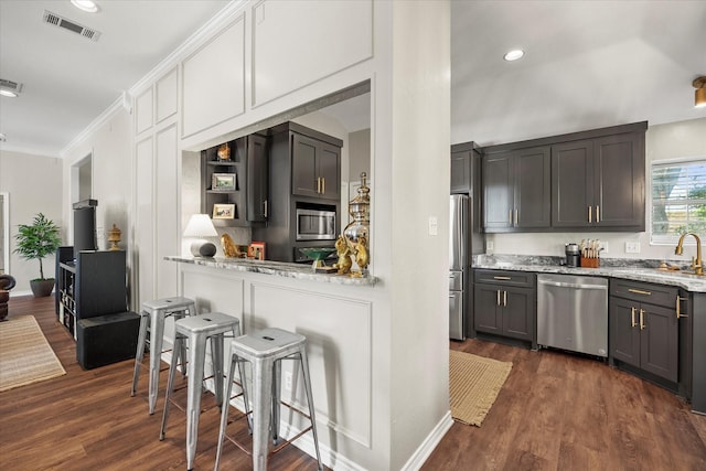 509 Windsor Way, Rockwall, TX 75087 - kitchen featuring appliances with stainless steel finishes, a sink, dark wood-style floors, a kitchen bar, and ornamental molding