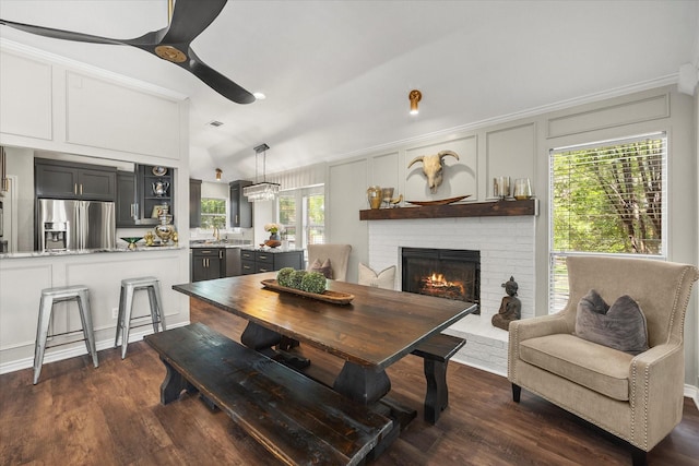 509 Windsor Way, Rockwall, TX 75087 - dining space featuring a ceiling fan, a fireplace, dark wood-style flooring, vaulted ceiling, and a decorative wall