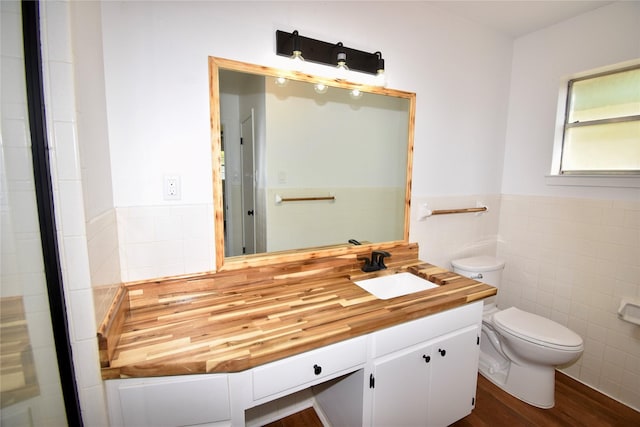 2013 S High St, Brady, TX 76825 - bathroom with tile walls, vanity, toilet, wood finished floors, and wainscoting