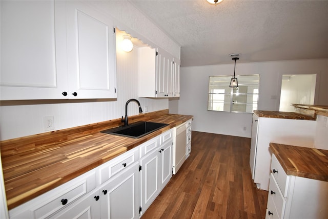 2013 S High St, Brady, TX 76825 - kitchen featuring wooden counters, a sink, dark wood finished floors, a textured ceiling, and white cabinets