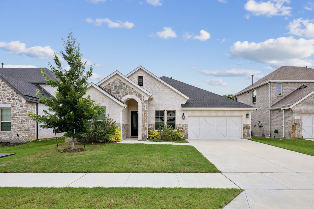 625 Lake Cove Dr, Little Elm, TX 75068 - french provincial home with an attached garage, stone siding, driveway, and a front lawn