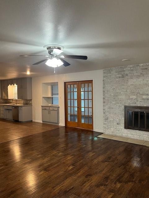 2411 Laredo Ct, Arlington, TX 76015 - unfurnished living room featuring a ceiling fan, french doors, a sink, wood finished floors, and a fireplace