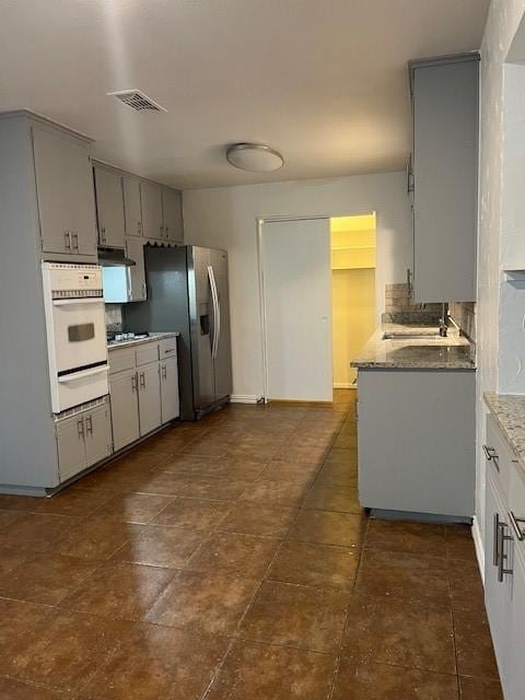 2411 Laredo Ct, Arlington, TX 76015 - kitchen featuring oven, gray cabinets, under cabinet range hood, a warming drawer, and stainless steel fridge with ice dispenser